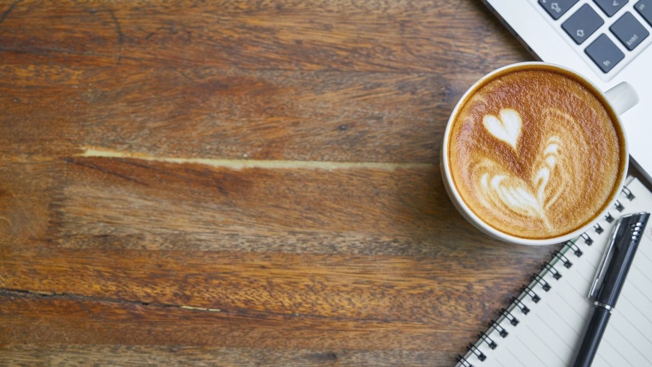 notebook, coffee, and laptop on a wood surface