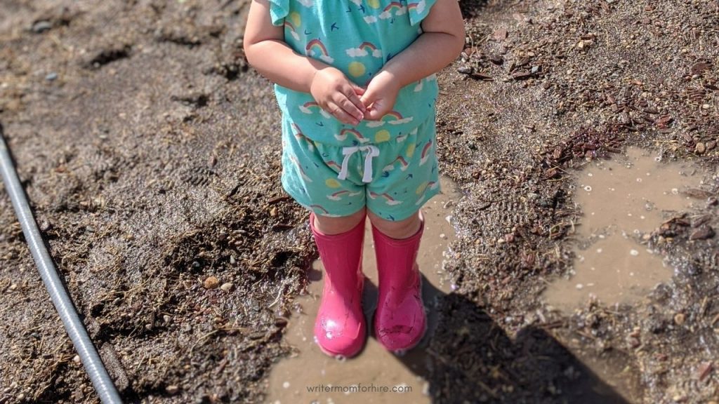 toddler wearing rain boots in the mud