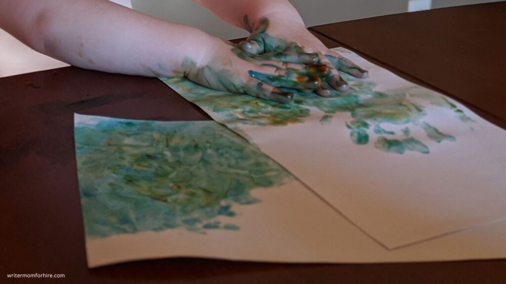 child using finger paints to learn about colors